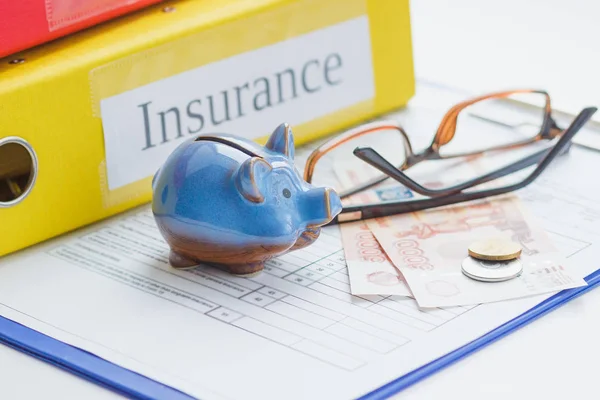 Sigorta formu, kumbara, gözlük ve para, yumuşak odak arka plan