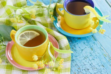 Ihlamur çiçekleri ve limon, yumuşak odak arka plan ile bitkisel çay bardak