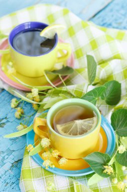 Ihlamur çiçekleri ve limon, yumuşak odak arka plan ile bitkisel çay bardak