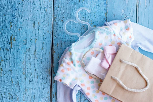 Different clothes for a newborn and paper package, top view