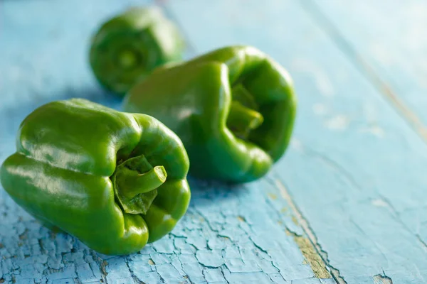Green peppers on the light blue wooden background