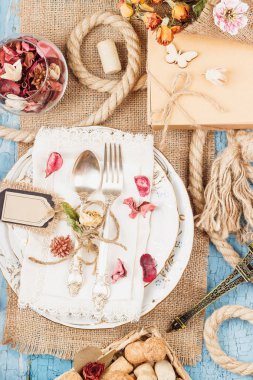 Sofra ve kuru çiçekler ve mavi eski ahşap arka plan üzerinde farklı süslemeler ile Gümüş eşyalar