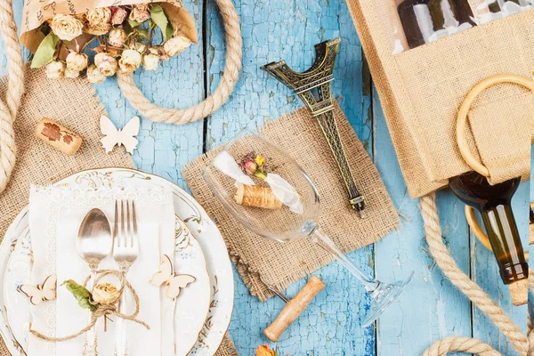 Sofra ve kuru çiçekler ve mavi eski ahşap arka plan üzerinde farklı süslemeler ile Gümüş eşyalar