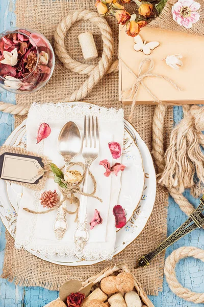 Sofra ve kuru çiçekler ve mavi eski ahşap arka plan üzerinde farklı süslemeler ile Gümüş eşyalar