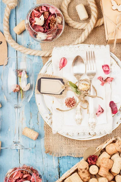 Sofra ve kuru çiçekler ve mavi eski ahşap arka plan üzerinde farklı süslemeler ile Gümüş eşyalar