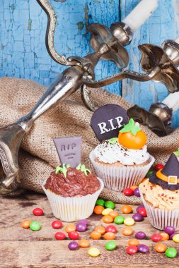 Renkli süslemeleri ile Halloween cupcakes: mezar taşı, cadı şapka ve şekerleme mastik, ahşap arka plan yapılmış kabak