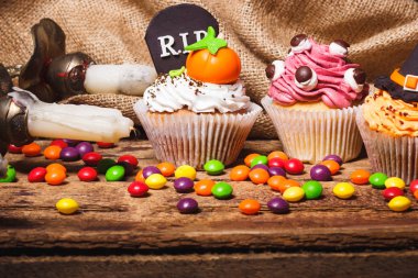 Renkli süslemeleri ile Halloween cupcakes: mezar taşı, cadı şapka ve şekerleme mastik, yumuşak odak arka plan yapılmış kabak