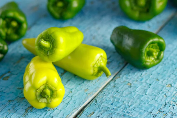 Green peppers on the light blue wooden background