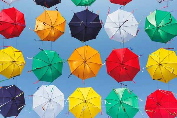 Colored umbrellas hanging above the street, view from the bottom