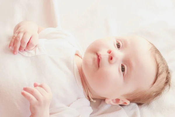 Bébé souriant sur le lit, fond de mise au point douce — Photo