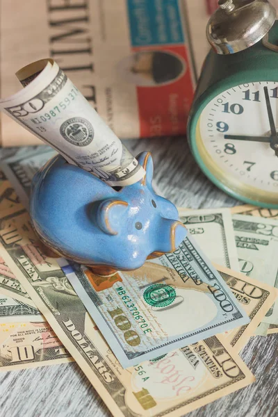 Piggy bank, alarm clock and American dollars, soft focus background