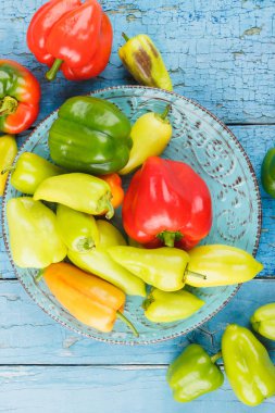 Mavi seramik tabak, hafif renkli biber ahşap arka plan mavi