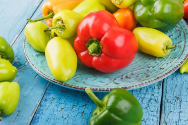 Mavi seramik tabak, hafif renkli biber ahşap arka plan mavi