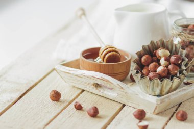 Ahşap kase, fındık ve kavanoz ahşap tepsi, yumuşak odak arka plan üzerinde süt ile tatlım