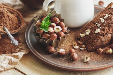 Parça çikolatalı kek, nane yaprağı, fındık ve kavanoz süt, yumuşak odak arka plan ile