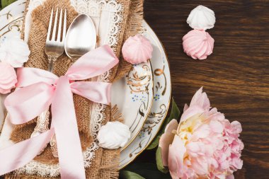 Masa hizmet: sofra ve süslemeleri ile gümüş. Hafif pembe peonies ve meringues ahşap arka plan üzerinde