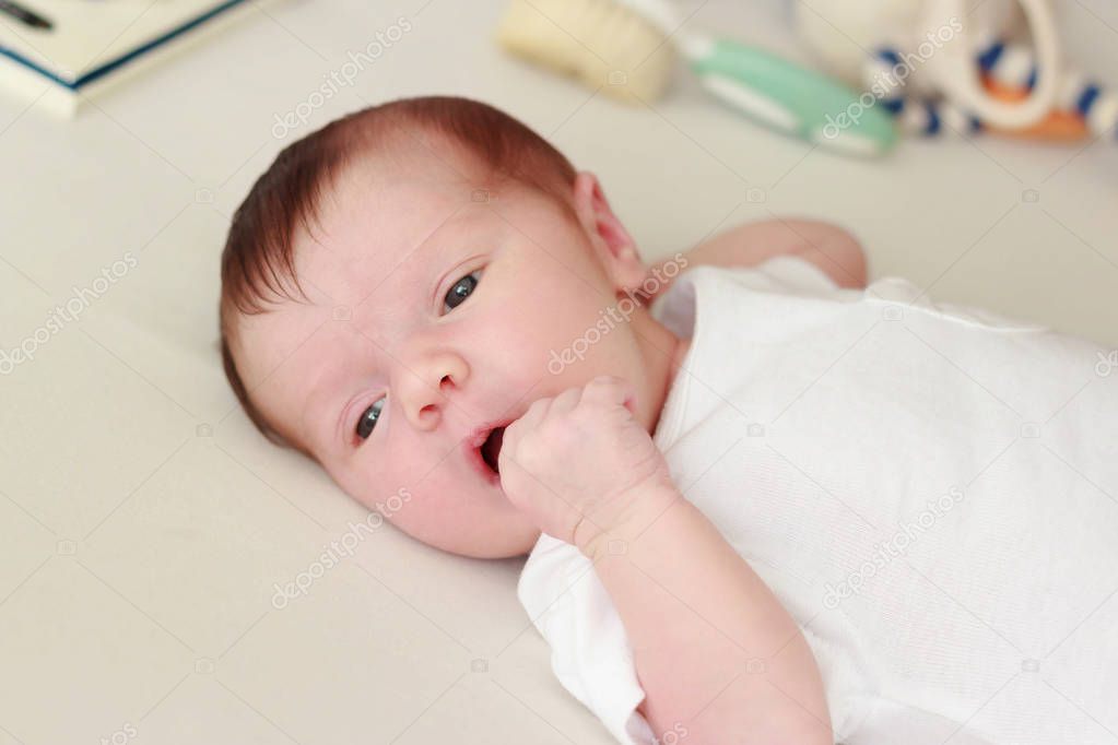 Newborn baby laying on a white blanket, blurred background