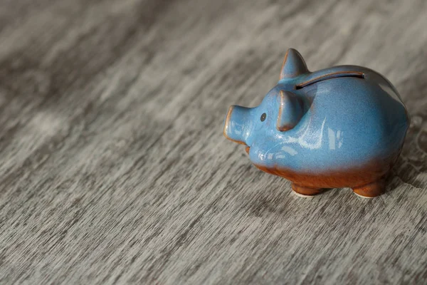 Blue piggy bank on the wooden background, soft focus background