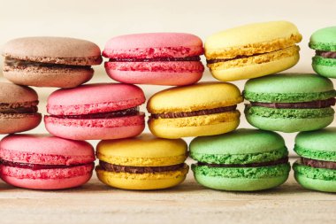 Yeşil, pembe, sarı ve kahverengi Fransız macarons ahşap kurullarında