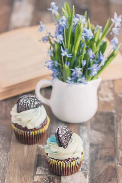 Muffins de chocolate feitos à mão com decorações. Livro e um buquê de Scilla, fundo borrado — Fotografia de Stock