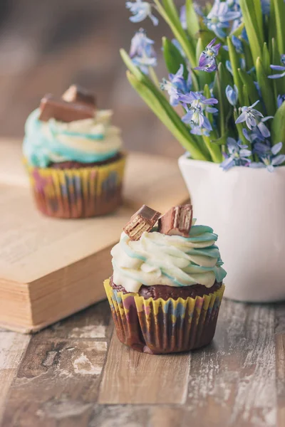 Muffins de chocolate feitos à mão com decorações. Livro e um buquê de Scilla, fundo borrado — Fotografia de Stock