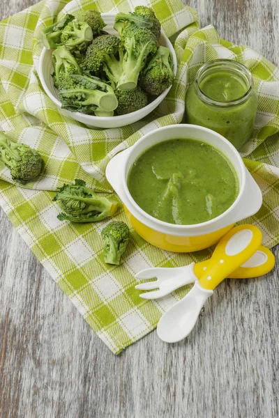 Fresh broccoli in the bowl, and portion of puree made from crushed, boiled broccoli