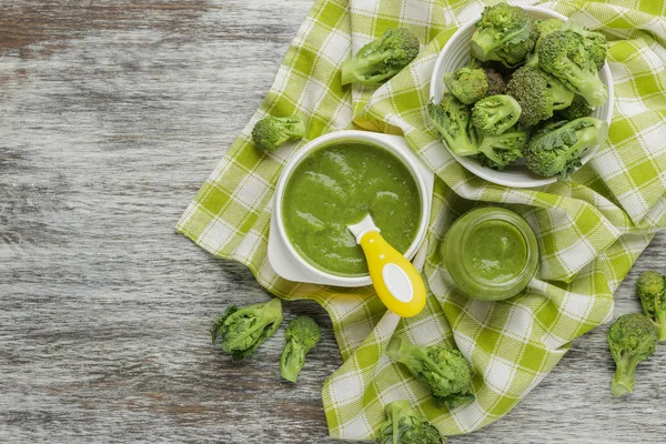 Fresh broccoli in the bowl, and portion of puree made from crushed, boiled broccoli