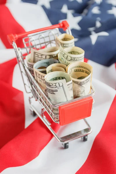 Carro de la compra con dólares americanos dentro en la bandera nacional de Estados Unidos de América — Foto de Stock