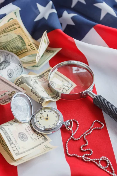 Кишенькові годинники, збільшувальне скло та долари США на національному прапорі Сполучених Штатів Америки — стокове фото