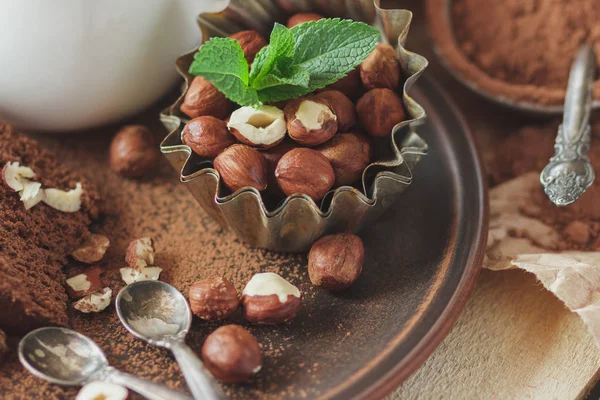 Bit chokladkaka, myntablad, hasselnötter och burk med mjölk — Stockfoto