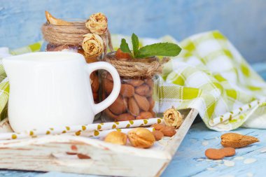 Ahşap tepside süt ile badem ve kavanoz, natürmort