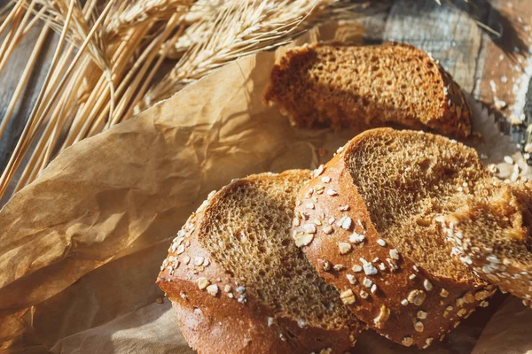 Handmade bread with bran and ears of wheat, wooden background