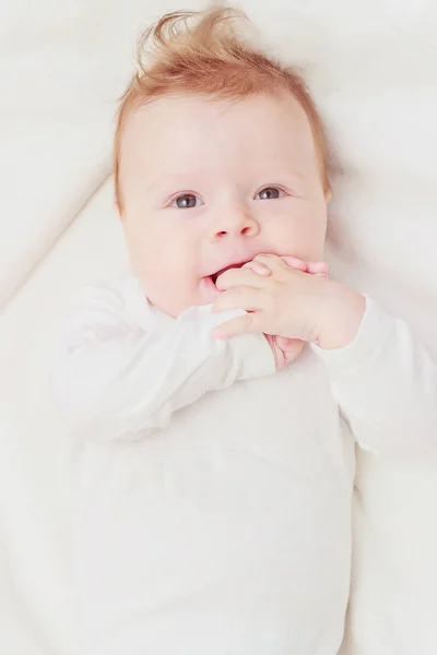 Happy child on the white blanket, blurred background — Stock Photo, Image