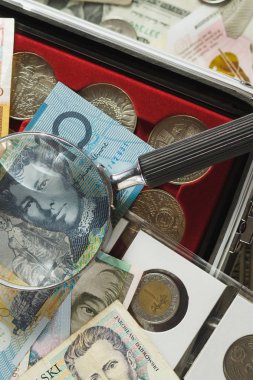 Farklı koleksiyoncu sikke ve banknot bir büyüteç ile
