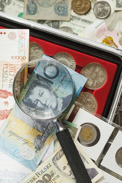 Различные коллекционные монеты и банкноты с увеличительным стеклом — стоковое фото