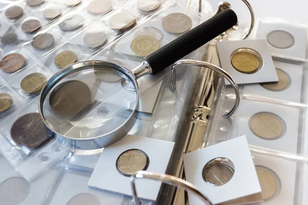 Different old collector's coins with a magnifying glass, blurred background  Stock Photo by ©lisssbetha@gmail.com 302688454