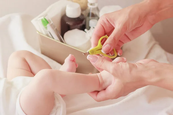 Bébé et les mains de la mère avec un bébé ciseaux, à l'intérieur, fond flou — Photo