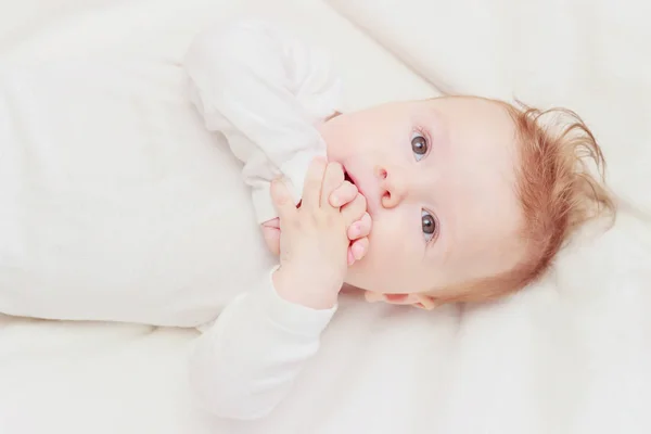 Happy Child på den vita täcket, suddig bakgrund — Stockfoto