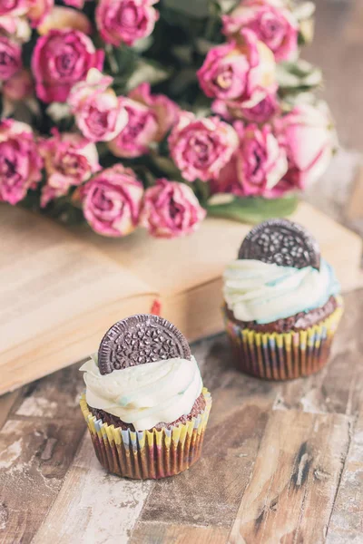 Muffins de chocolate feitos à mão com decorações. Livro e um buquê de rosas — Fotografia de Stock