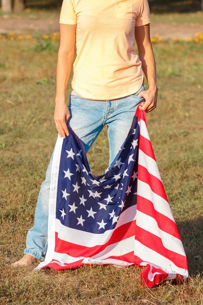 Mujer con una bandera de Estados Unidos de América en las manos, al aire libre —  Fotos de Stock