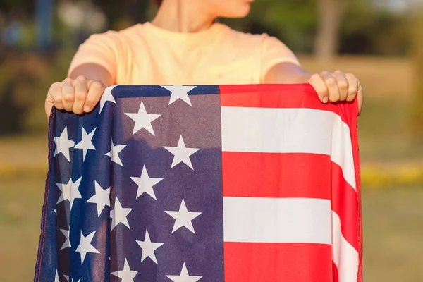 Mujer con una bandera de Estados Unidos de América en las manos, al aire libre —  Fotos de Stock