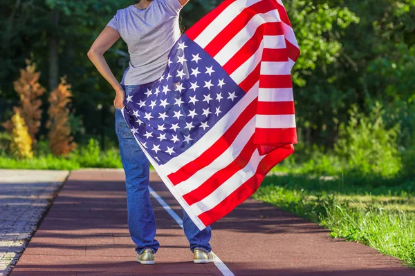 Mujer con una bandera de Estados Unidos de América en las manos, al aire libre —  Fotos de Stock