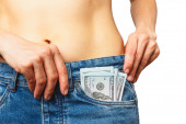 Slim krásná žena nosí džíny se sto dolary bankovky v kapse, izolované