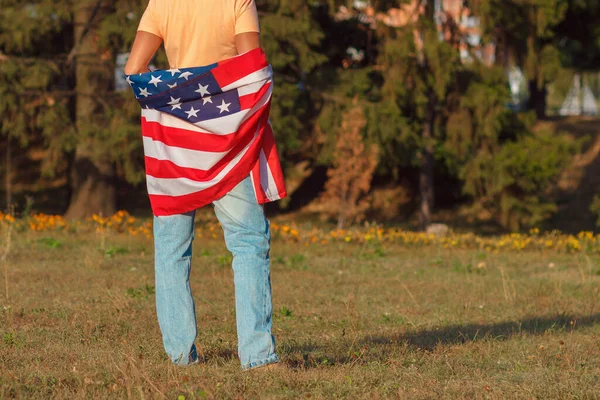 Woman with a flag of United States of America in the hands, outdoors, soft focus background