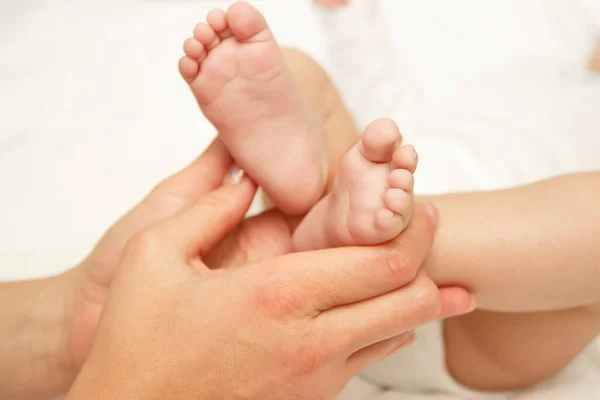 女性の手は赤ちゃんの足を保持し ソフトフォーカスの背景 — ストック写真