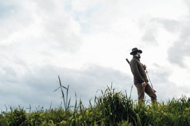 Eski avcı yürüyüşleri. Tüfek Avcısı Silhouetted in Beautiful Sunset or Sunrise. Avcı bataklıkta ve tarlada tüfeği hedefliyor