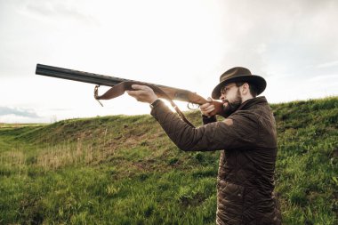 Eski avcı yürüyüşleri. Tüfek Avcısı Silhouetted in Beautiful Sunset or Sunrise. Avcı bataklıkta ve tarlada tüfeği hedefliyor