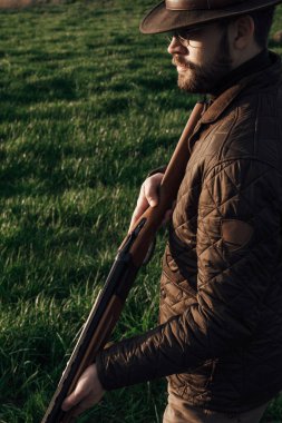 Eski avcı yürüyüşleri. Tüfek Avcısı Silhouetted in Beautiful Sunset or Sunrise. Avcı bataklıkta ve tarlada tüfeği hedefliyor