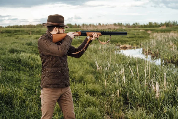 Vintage hunter walks. Rifle Hunter Silhouetted in Beautiful Sunset or Sunrise. Hunter aiming rifle in swamp and field