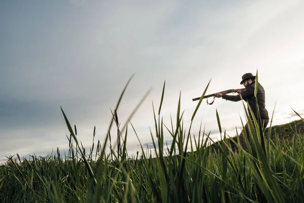 Vintage hunter walks. Rifle Hunter Silhouetted in Beautiful Sunset or Sunrise. Hunter aiming rifle in swamp and field